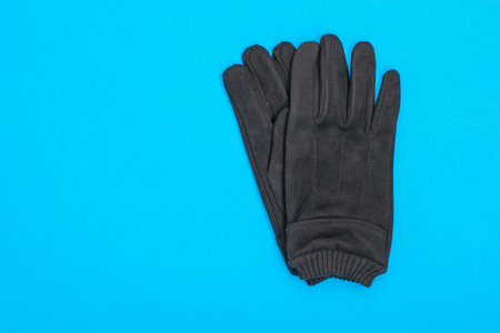 A pair of men's suede gloves on a blue background. Men's accessory for cool weather. The view from the top.の写真素材
