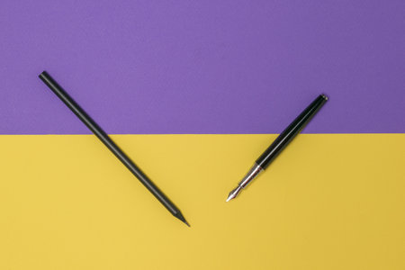 Fountain pen and black pencil on a yellow and purple background. Stylish stationery.の写真素材