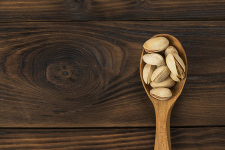 Wooden spoon with pistachio nuts on a wooden table. A natural source of protein and carbohydrates.の写真素材
