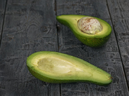 An avocado cut in half on a wooden table. Plant-based food.の写真素材