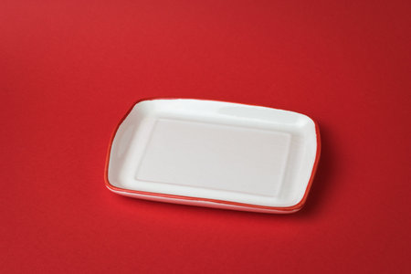 White Cup with a red border on a red background. Dishes on red.の写真素材