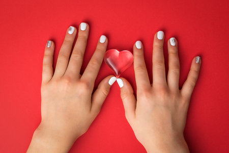 Hands of a girl with a glass heart on a red background. A symbol of love and life.の写真素材