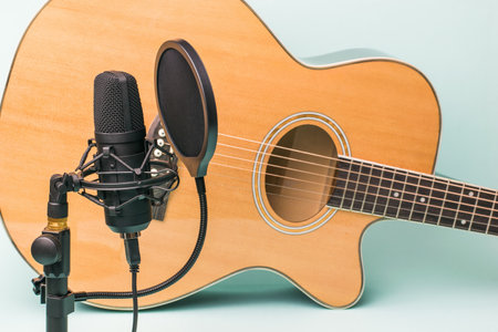 Modern microphone on the background of a six-string guitar. Record and play music.の写真素材