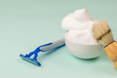 A shaving brush in a bowl with shaving foam on the background of a disposable razor. Set for care of a man's face.の写真素材