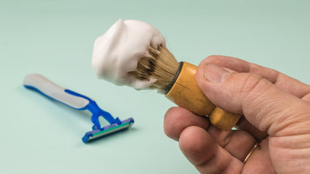 Shaving brush with shaving foam in the hands of a man on a light background. Set for care of a man's face.の写真素材