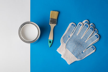 An open can of white paint, gloves and a brush on a blue and white background. Execution of painting works.の写真素材