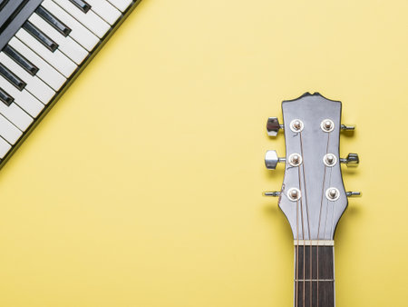 Acoustic guitar neck and piano keys on a yellow background. Musical instruments.