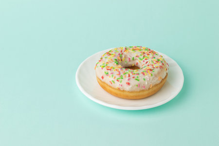 Glazed donut on a white plate on a blue background. A popular confection.の写真素材