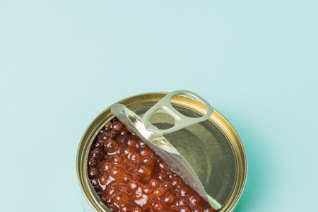 Red caviar in an open iron jar on a blue background. Natural healthy marine product.の写真素材