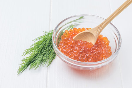 A wooden spoon in a glass bowl with red caviar. Natural healthy marine product.の写真素材