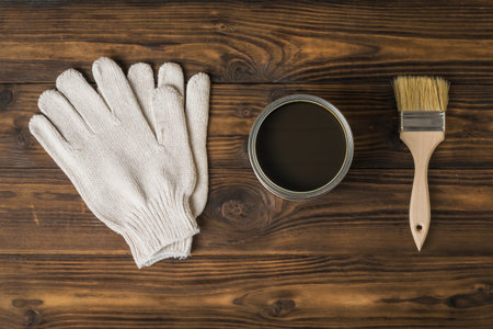 Brush, gloves and jar with a protective coating for wood on a wooden background. The rendering of wood.の写真素材