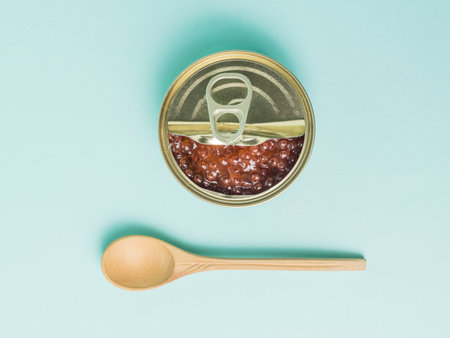 A wooden spoon next to an open jar of red caviar on a blue background. Natural healthy marine product.の写真素材