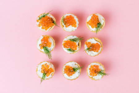 Tartlets filled with red caviar and cream cheese on a pink background. Appetizer with sea delicacies.の写真素材