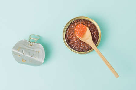 An iron jar with the lid removed filled with red caviar on a blue background. Natural healthy marine product.の写真素材
