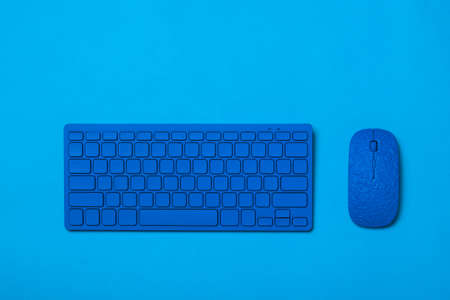 Blue wireless keyboard and mouse on a blue background. Monochrome image of office accessories.の写真素材