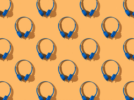 A pattern of bright blue headphones on an orange background. Mobile audio playback equipment.の写真素材