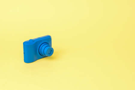 The camera is in a bright blue color on a yellow background. Stylish equipment for photo and video...