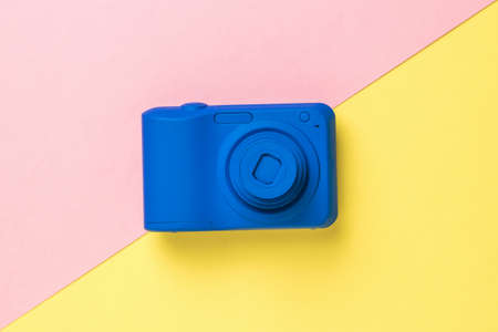 Top view of a blue camera on a yellow and pink background. Stylish equipment for photo and video shooting.の写真素材