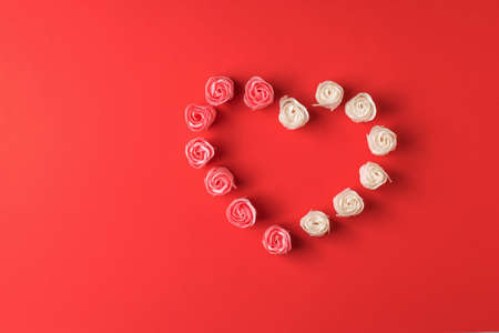 Heart of red and white rose buds on a red background. The concept of love.