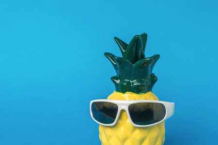 Pineapple wearing black glasses on a blue background. Summer concept.の写真素材