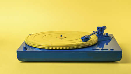 Blue and yellow vintage vinyl record player on a yellow background. Retro music equipment.の写真素材