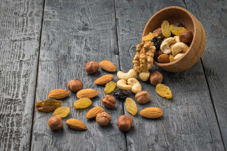 An inverted wooden bowl with dried fruits and nuts on a wooden table. Natural healthy vegetarian...