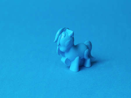 A blue pony toy on a blue background. Monochrome image of a fashionable toy.