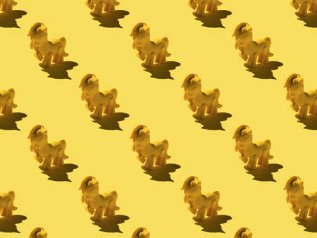 A pattern of yellow pony toys on a yellow background. Monochrome image of a fashionable toy.の写真素材