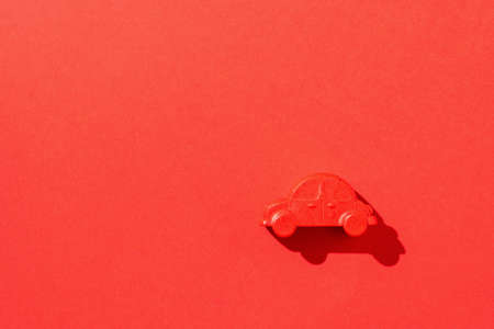 A red car figure on a red background in a bright light. The concept of a popular vehicle. Flat lay.の写真素材