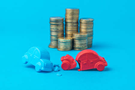 Installation of a car accident with toy cars on the background of coins. The concept of a road...
