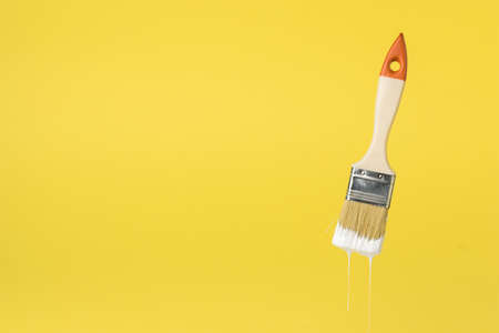 Brush with dripping white paint on a white background. Space for the text. Execution of painting...