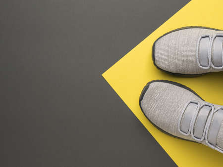 Top view of light gray sneakers on a yellow and dark gray background. Sports lifestyle. Colors 2021. Flat lay.の写真素材