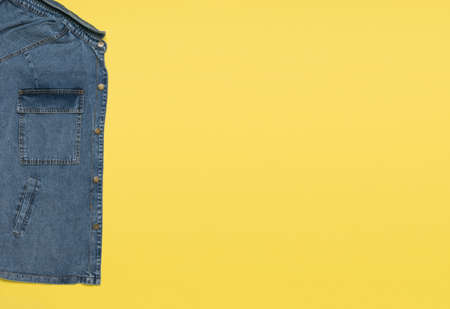 Part of a blue denim jacket on a yellow background. Popular casual clothing.の写真素材