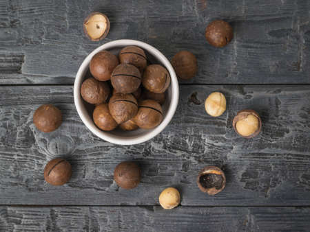 Top view of macadamia nuts in a ceramic bowl on a piece of cloth on a wooden table. Superfood.の写真素材