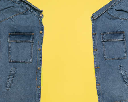 An unbuttoned blue denim jacket with a yellow background inside. Popular casual clothing.の写真素材