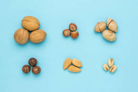 Piles of various unpeeled nuts on a blue background. Vegetarian food.の写真素材