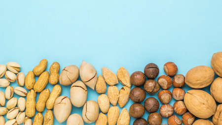 A mixture of different nuts on a light blue background. Vegetarian food.の写真素材