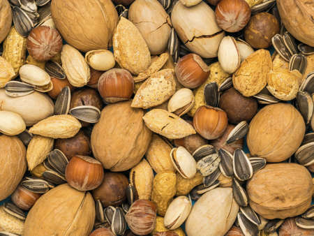 The background is made from a mixture of a large number of unpeeled nuts. Vegetarian food.