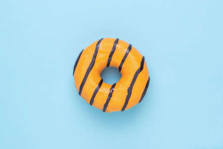 A bright carbonated orange donut on a blue background. Delicious popular pastries.の写真素材