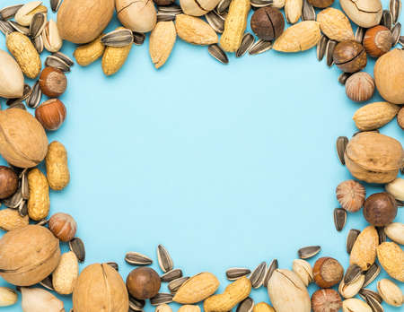 The frame is made of a mixture of nuts on a blue background. Vegetarian food.の写真素材