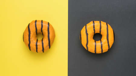 Orange donuts glazed with chocolate on a yellow and black background. Delicious popular pastries.の写真素材