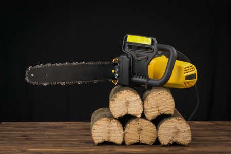 Electric chain saw on sawn wooden logs. Electric tool for wood processing.の写真素材