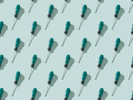 A pattern of screwdrivers on a light blue background. Hand tool for screws, bolts and screws.