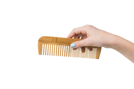 Female hand with stylish wooden comb isolated on white background. Tools for hair care.