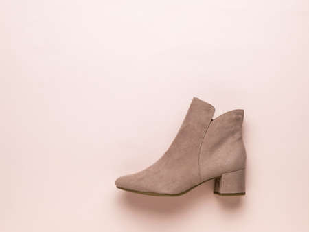 Light women's beige suede boot on a light beige background. Stylish demi-season women's shoes. Flat...