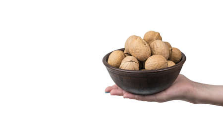 A woman's hand with a large bowl filled with walnuts isolated on a white background. A popular type...