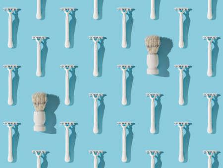 A pattern of white razors and two brushes on a blue background. Plastic razor for men's shaving. Flat lay.の写真素材