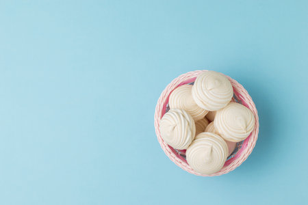Top view of a basket of fresh meringue on a blue background. Delicious sweetness of eggs and sugar.の写真素材