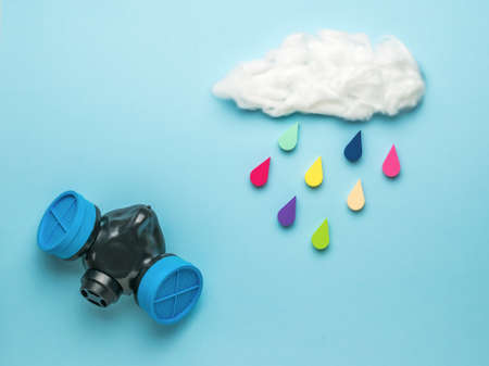 A gas mask and a cloud with falling multicolored drops on a blue background. Spraying and protection against toxic substances. Collage of modern art. Climate picture.の写真素材