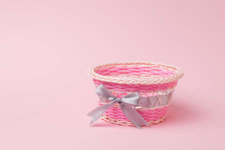 Pink wicker basket on a light pink background. An item for decorating a festive table.